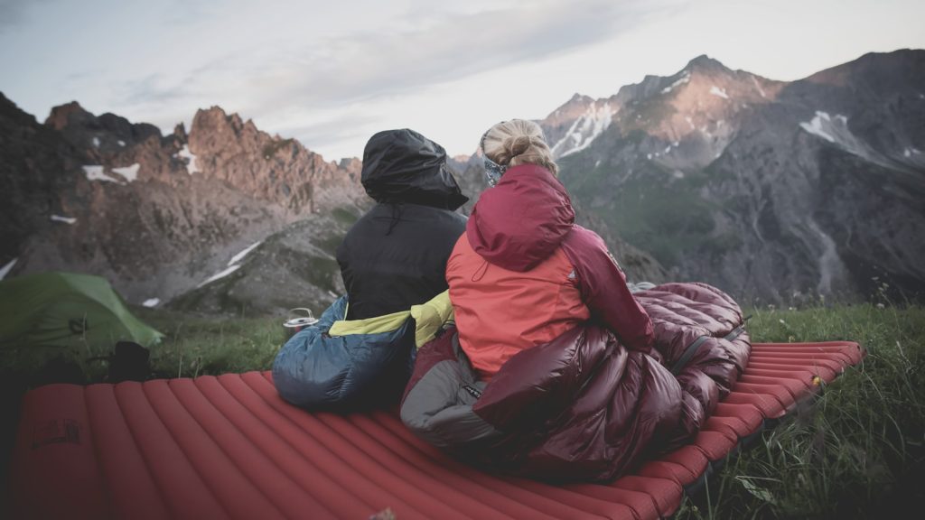 Sleeping Bag Types: Mummy vs. Rectangular – Which One is Right for You? a couple of people sitting on top of a red blanket