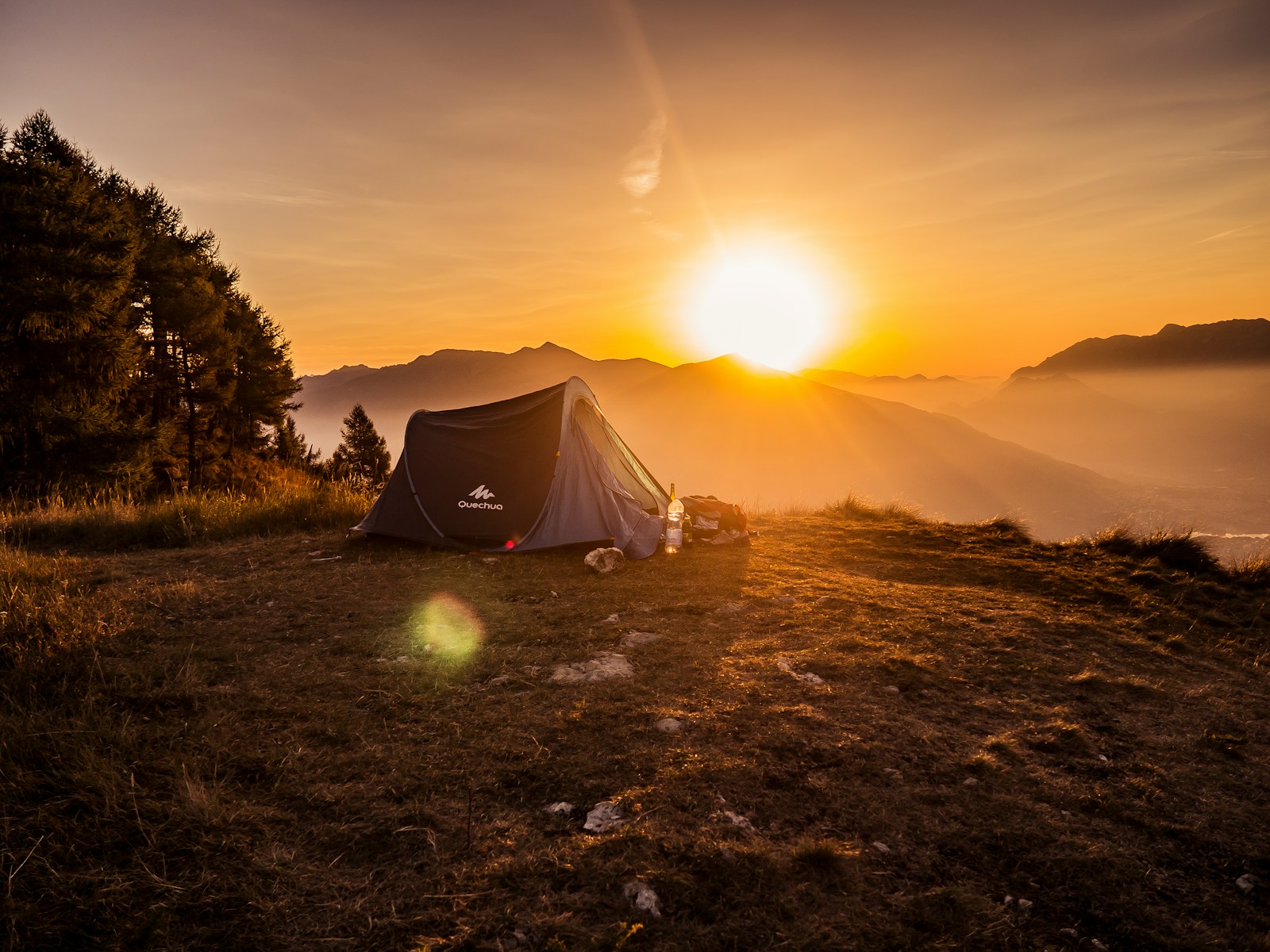 The Ultimate First-Time Camping Essentials: A Beginner’s Checklist dome tent on mountain top with sun as background photo