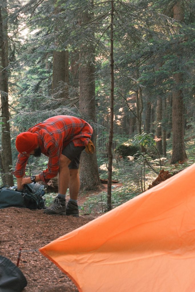 Camping Tips Man packs his backpack in a forest.