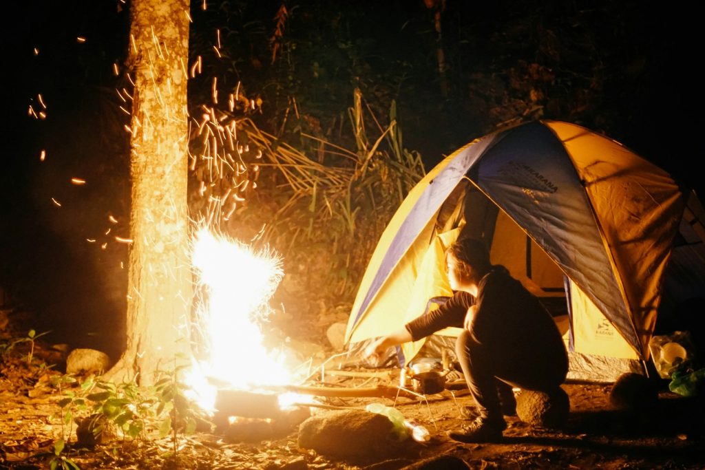 Camping Safety Tips Everyone Should Know man cooking beside dome tent taken at nighttime