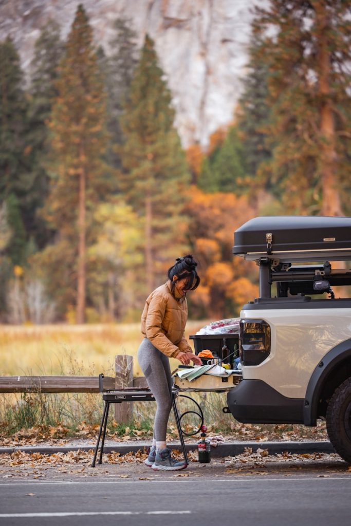 Woman cooking outdoors with a camper van