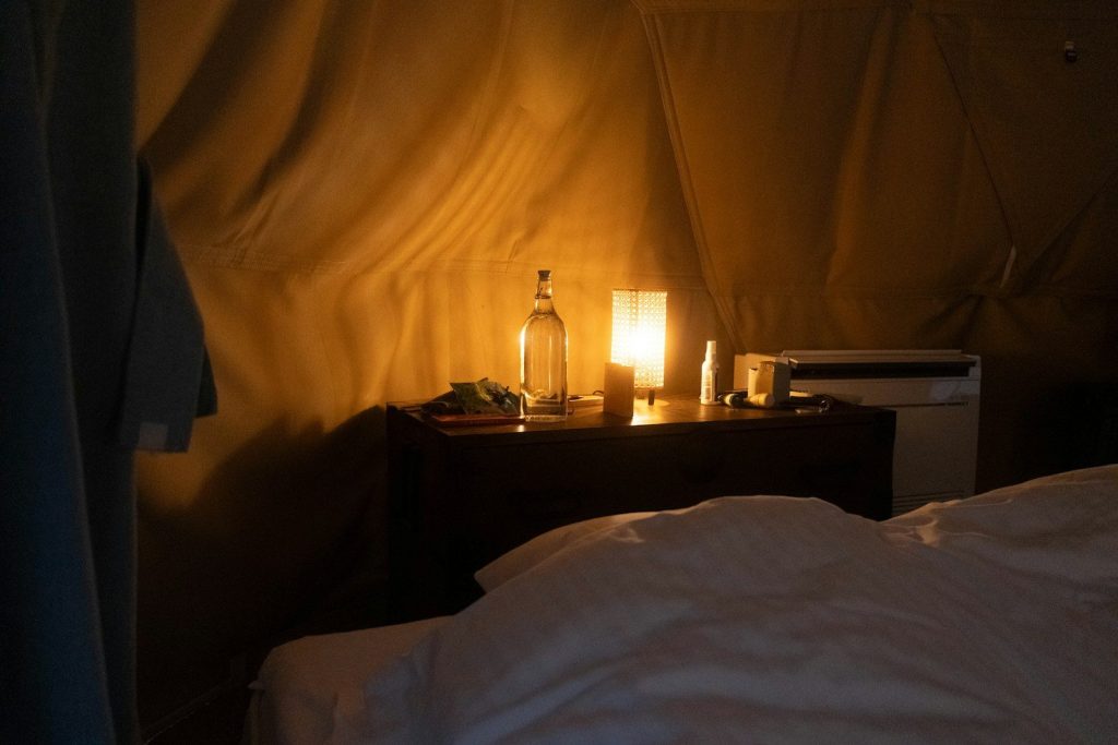 A bedside table with a lamp and water bottle.