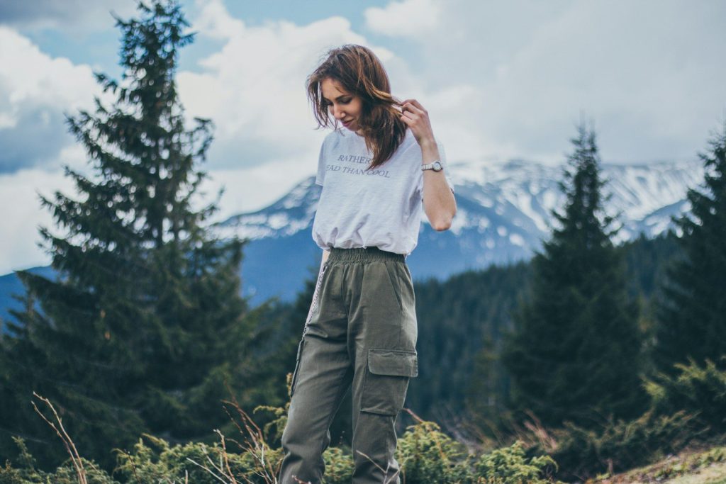 Best Convertible Hiking Pants woman in grey shirt and green cargo pants standing on mountain top