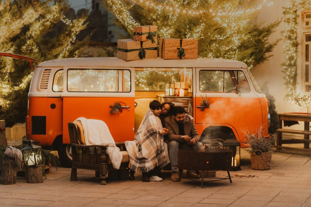 Family gathered around a campfire by a vintage van