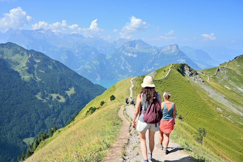 Two women hiking on a mountain trail with scenic views.