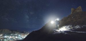 man holding turned-on flashlight standing on the cliff