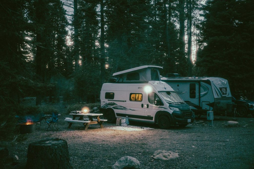 Best Camping Lights with Power Bank: Vetted Multi-Functional Lanterns Illuminated camper van and picnic table at a forest campsite.