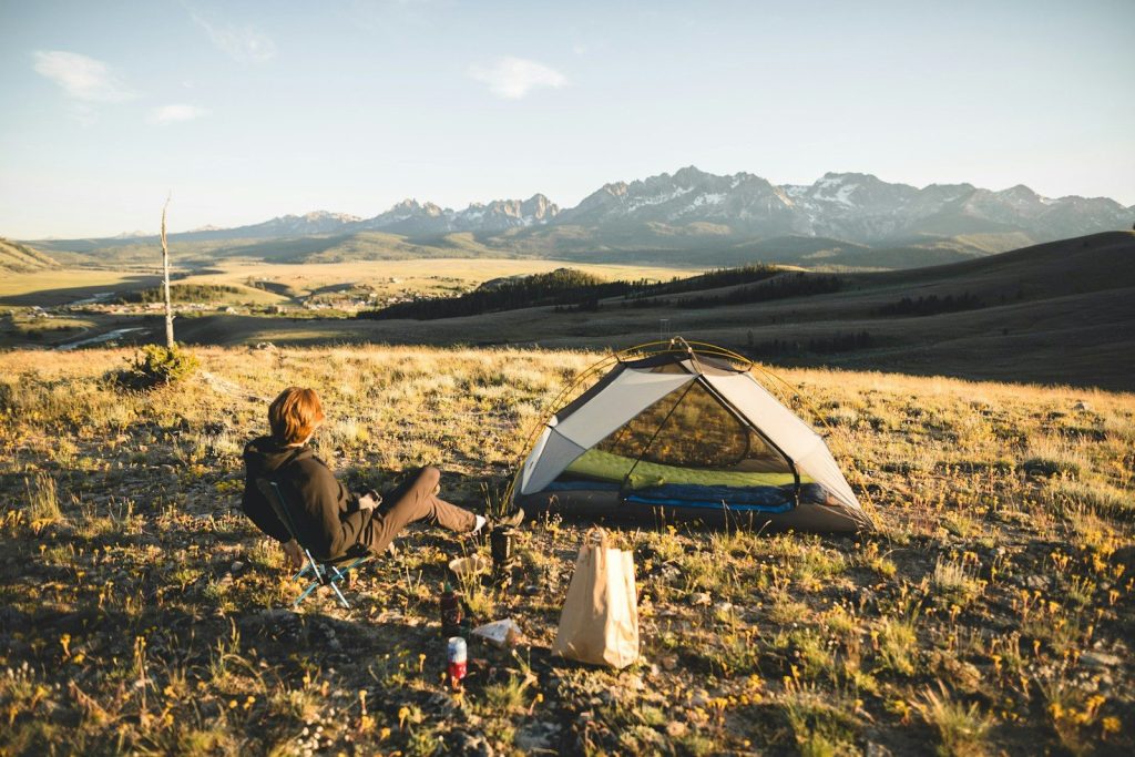 Safety Tips for Solo Camping: Essential Guide for a Safe and Confident Outdoor Adventure woman in black jacket sitting on green grass field near tent during daytime