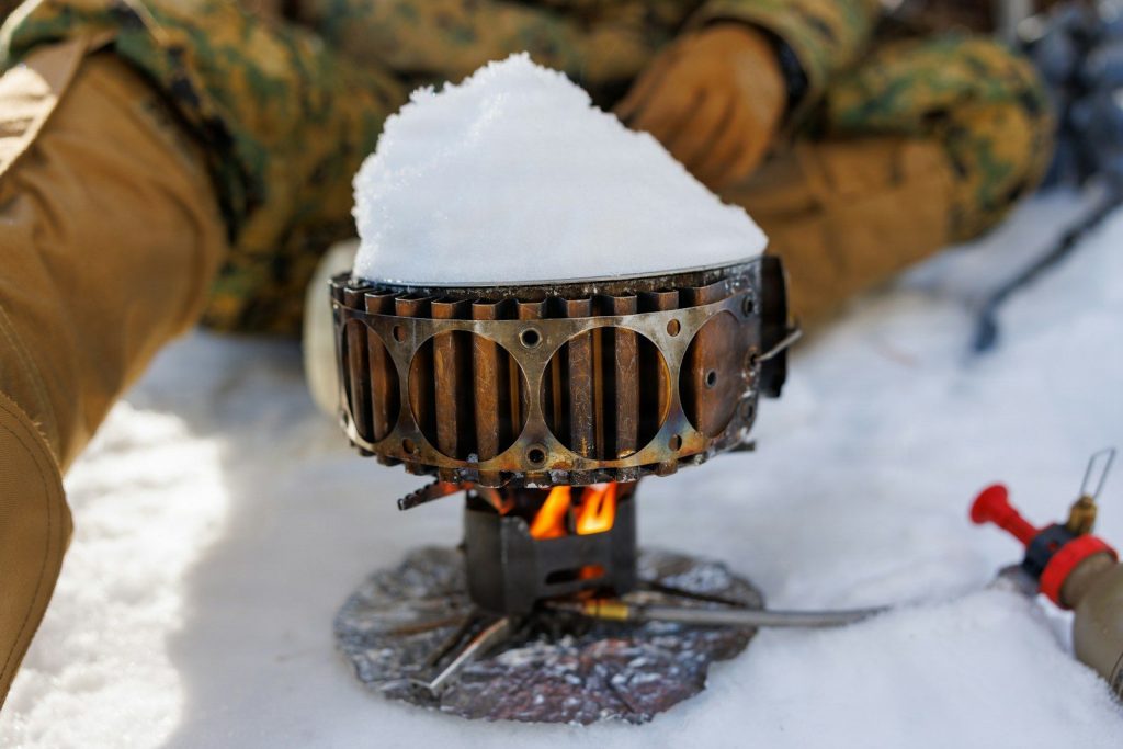 Best Stoves for Winter Camping: Vetted Sub-Zero Cooking Systems A portable stove melts snow with a flame.