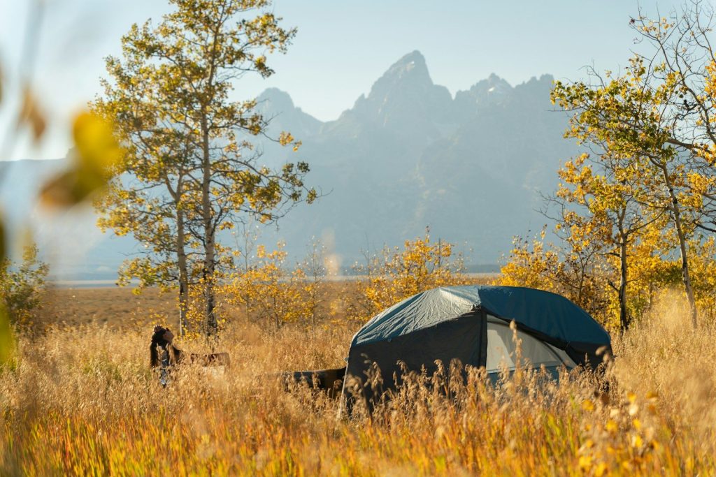Tent set up in a field with mountains behind