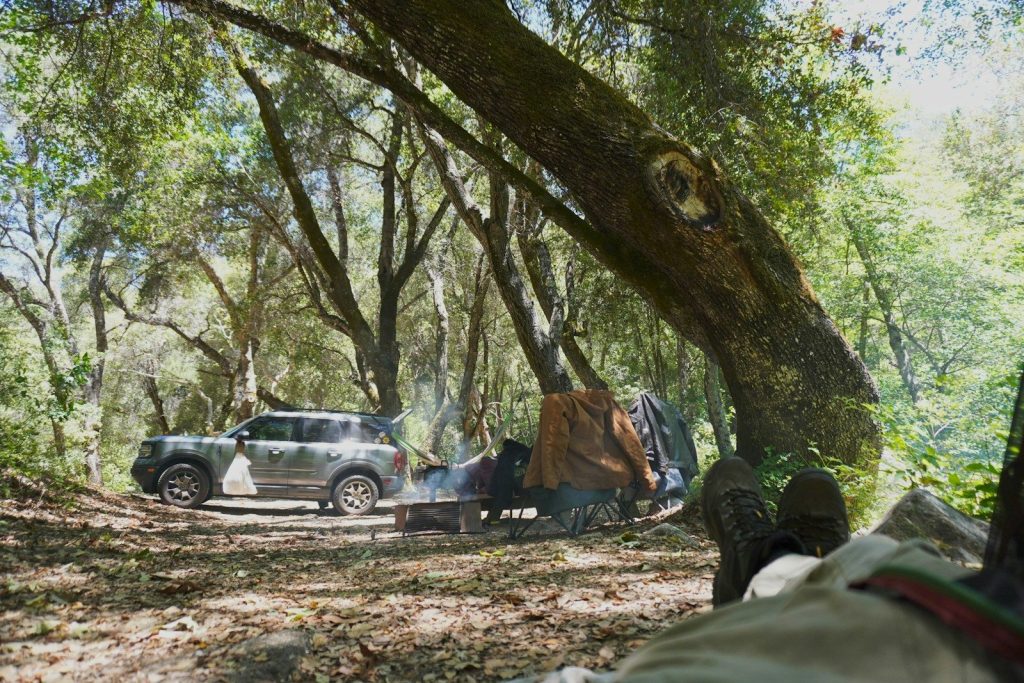 Suv towing a camping trailer in a dense forest.