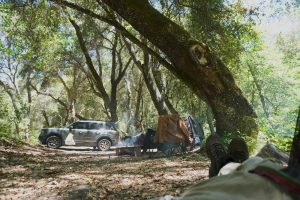 Suv towing a camping trailer in a dense forest.