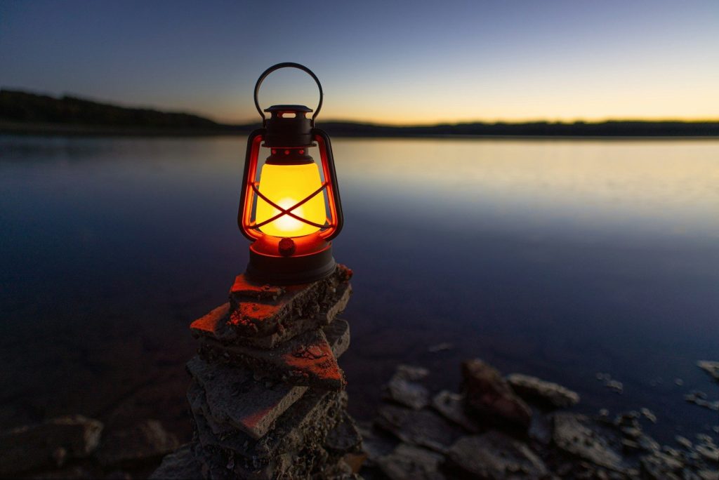 Lantern vs Headlamp: The Ultimate Backcountry Illumination Guide turned-on gas lamp on rock beside sea
