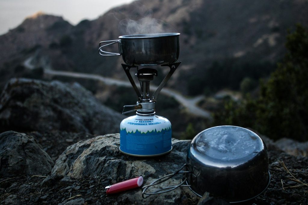 Best Camping Stoves for Cold Weather: Vetted Sub-Zero Cooking Engines selective focus of blue and gray camping gas burner and cooking pan on cliff